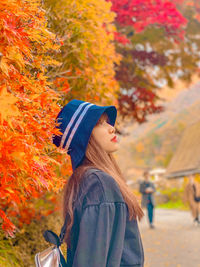 Side view of woman against orange trees during autumn