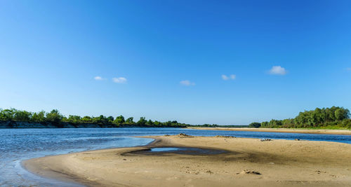 Scenic view of beach against blue sky