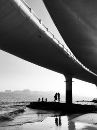 People on bridge over sea against sky