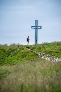 Woman standing next to crucifix on alpine footpath in the austrian alps, loser mountain region