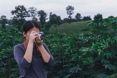 Young woman photographing on field