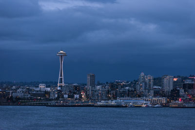 Illuminated buildings in city against cloudy sky