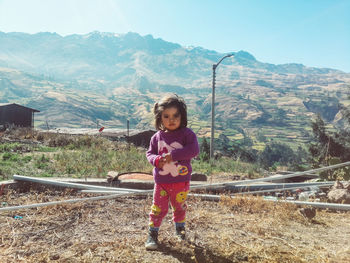 Portrait of cute girl standing on mountain against sky