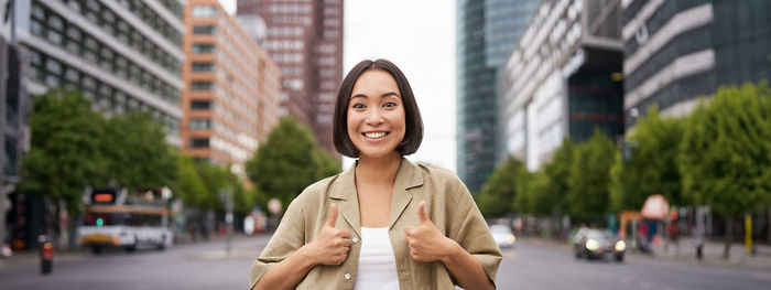 Portrait of young woman standing in city