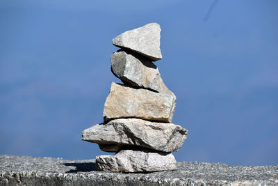 Low angle view of stone stack on rock against sky