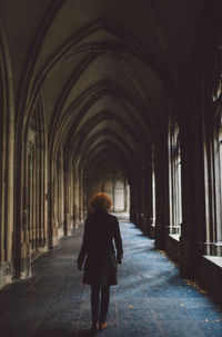 Rear view full length of woman standing in historic church corridor