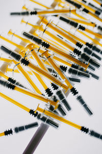 High angle view of yellow syringes against white background