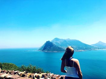 Rear view of woman looking at sea against mountain