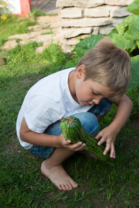 Cute boy holding vegetable on field