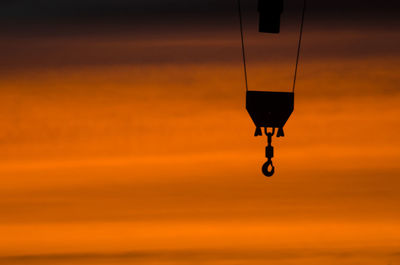 Silhouette hook hanging against sky during sunset