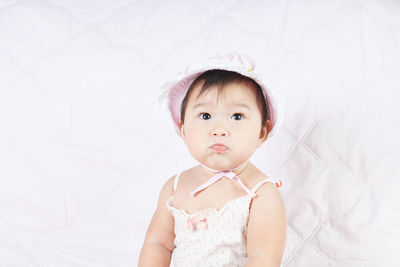 Cute baby girl sitting on bed at home