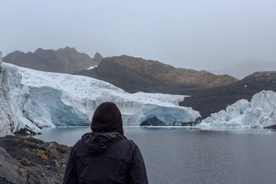 Rear view of woman looking at mountain and lake during winter