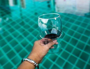Cropped image of man drinking glass in swimming pool