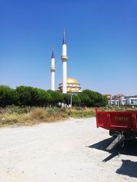 Street amidst buildings against clear blue sky