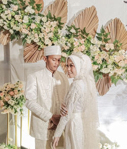 Midsection of couple standing against white wall