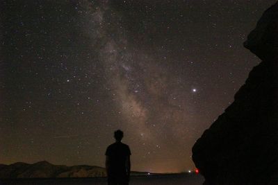 Rear view of silhouette man standing against star field