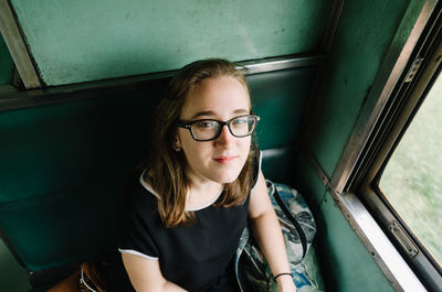 Portrait of smiling mid adult woman sitting in window