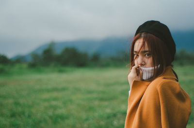 Close-up of young woman in field against sky