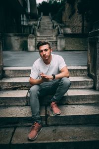 Portrait of young man sitting on staircase