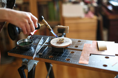 Home workshop girl master on a gas burner in a meta-liter scoop boils water with a copper plate, 