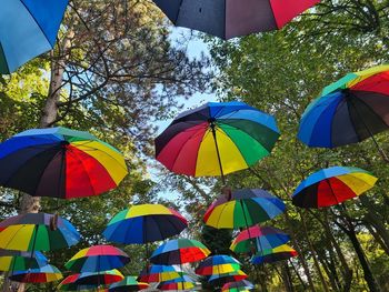 Low angle view of multi colored umbrellas hanging against sky