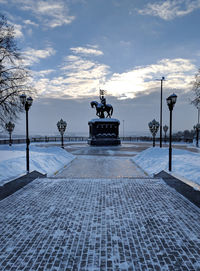 View of fountain at street against cloudy sky