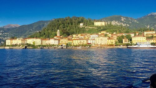 Buildings by sea against blue sky