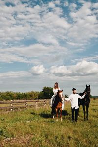 Couple riding horse on field