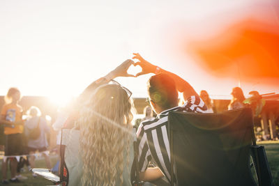 Group of people at music concert against sky during sunset
