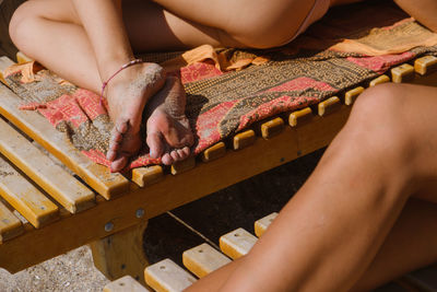 Low section of woman sitting on wood