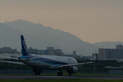 Airplane on airport runway against sky