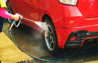 Midsection of person by red car