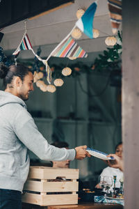 Smiling man giving plate to friend at dining table