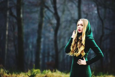 Woman in witch costume looking away while standing at forest