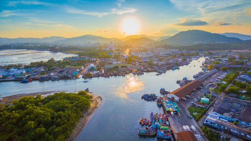 High angle view of cityscape by sea against sky during sunset