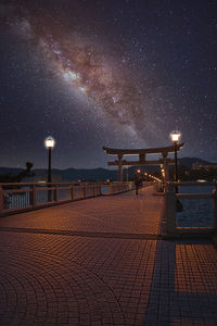 Illuminated pier against sky at night