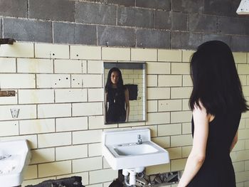 Woman standing by mirror at abandoned building
