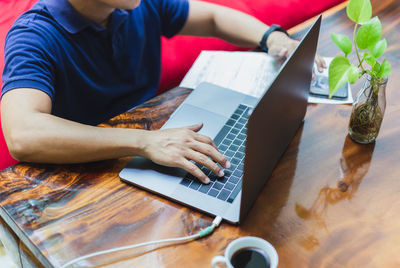 Midsection of man using laptop on table