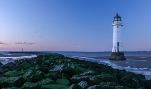 Lighthouse amidst sea and buildings against sky