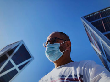 Low angle portrait of man against clear blue sky