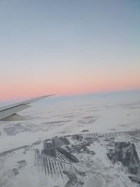 Scenic view of snow covered land against sky during sunset