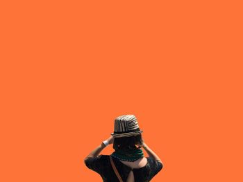 Close-up of woman photographing against orange background