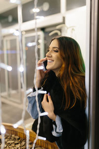 Young girl laughing while talking on cell phone with lights around