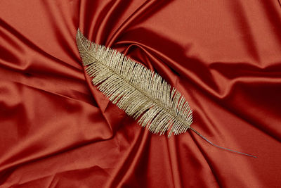 Decorative golden leaves on red textile backdrop. bright, glamour autumnal concept with fake fall