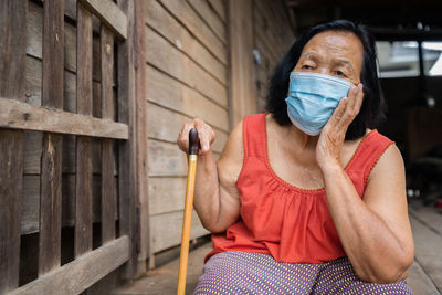 Senior woman wearing mask sitting outdoors