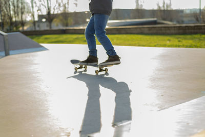 Low angle view of skater legs riding on skatepark in sunset