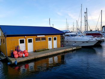 Sailboats moored at harbor against sky