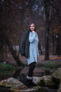 Woman standing by tree in forest