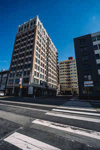 Road by buildings against sky in city