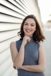 Portrait of young woman standing by blinds